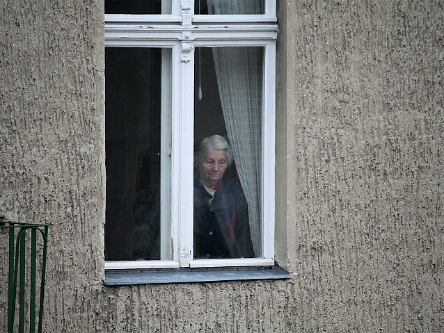 Smutna starsza kobieta patrzy przez okno