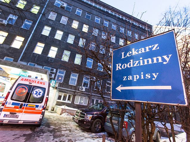 Napis: Lekarz rodzinny - zapisy. W tle szpital i karetka