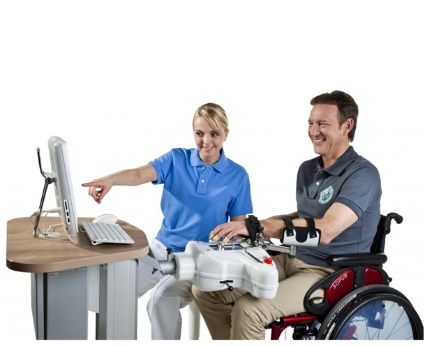Mężczyzna siedzący na wózku inwalidzkim, obsługującego program Amadeo. Obok niego siedzi pielęgniarka