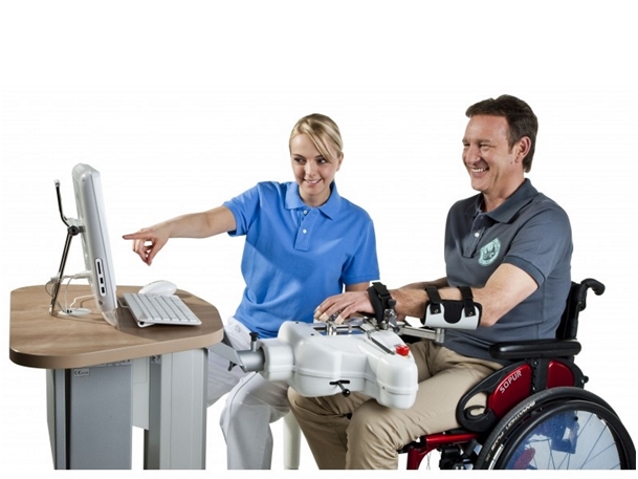 Mężczyzna siedzący na wózku inwalidzkim, obsługującego program Amadeo. Obok niego siedzi pielęgniarka
