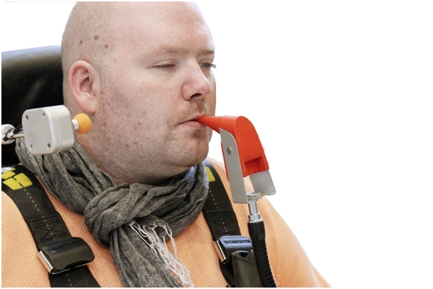 Mężczyzna na wózku trzymający w ustach urządzenie IntegraMouse Plus