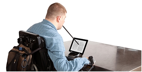 Mężczyzna siedzący na wózku obsługujący tablet za pomocą MouthStick Stylus trzymanego w ustach.