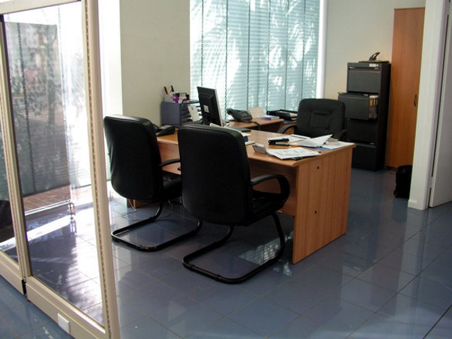 biuro, w którym znajduje się biurko i krzesło oraz dwa krzesła naprzeciwko biurka