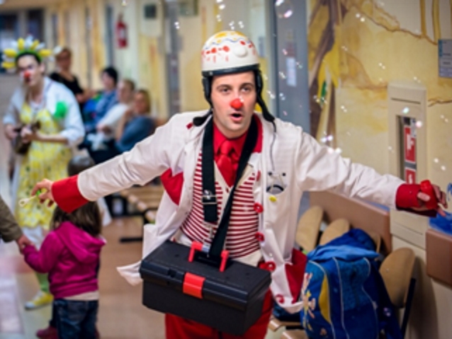 klaun lekarz biegnie przez korytarz w szpitalu, w celu rozśmieszenia dzieci