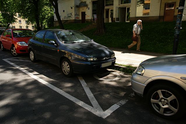 Samochód zaparkowany na kopercie. Przed nim i za nim także zaparkowane samochody