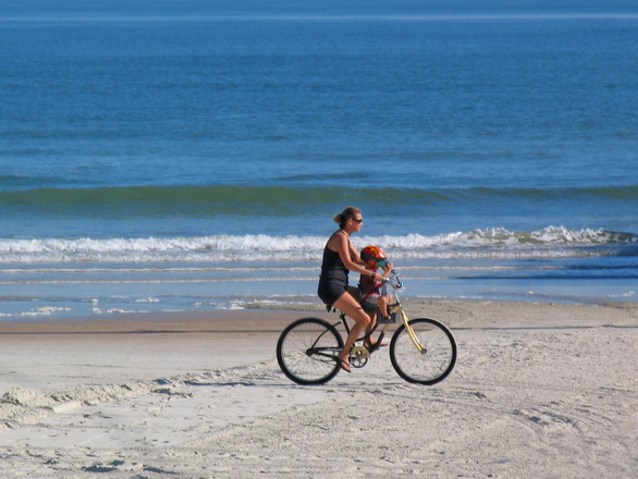 mama jedzie z dzieckiem na rowerze na plaży