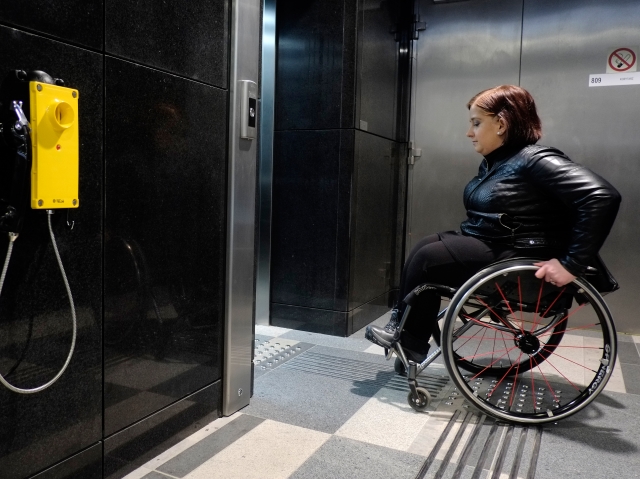 kobieta na wózku inwalidzkim wjeżdża do windy w metrze