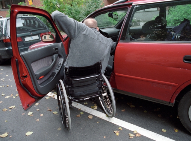 mężczyzna na wózku inwalidzkim stara się wsiąść do samochodu