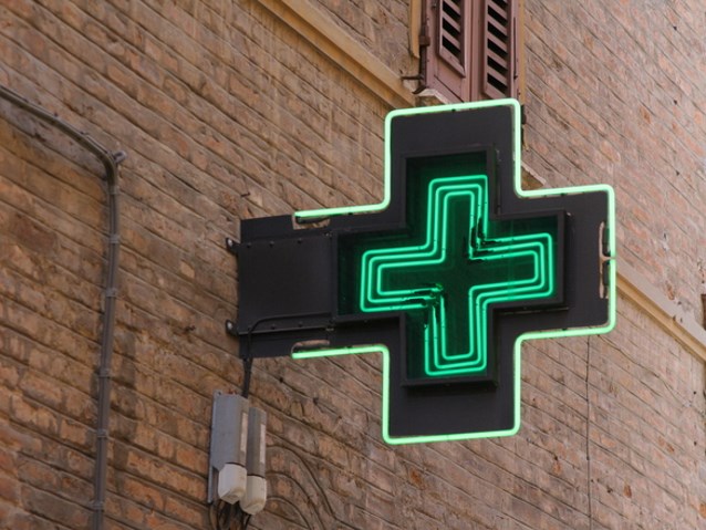 Neonowy zielony krzyż wiszący na budynku apteki