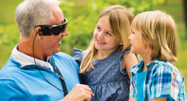 czarne okulary na twarzy starszego mężczyzny, który śmieje się do dwójki wnuków