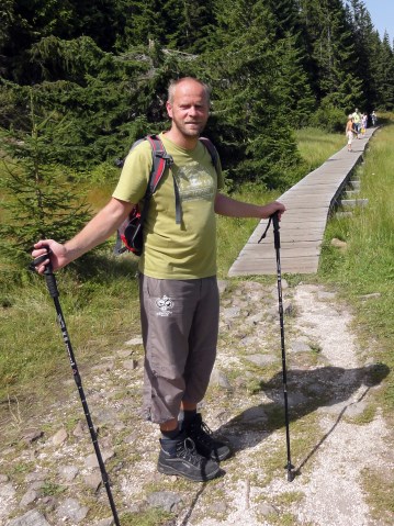 Jan Szuster w górach, stoi podczas przystanku w wędrówce, wspierając się na kijkach