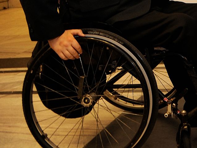 Koło wózka inwalidzkiego z fragmentem ręki użytkownika