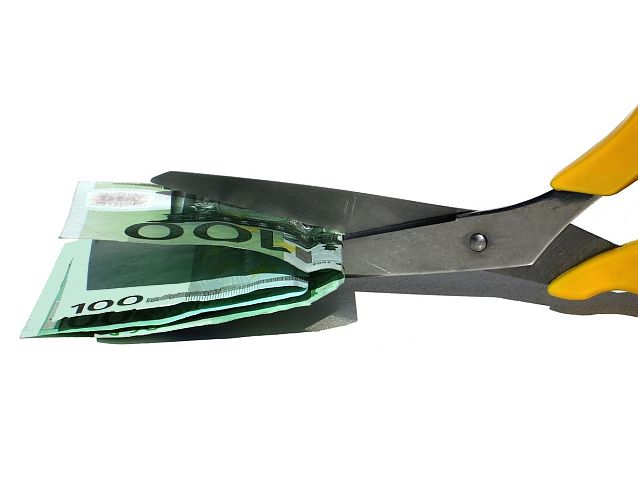 Nożyczki przecinają plik banknotów