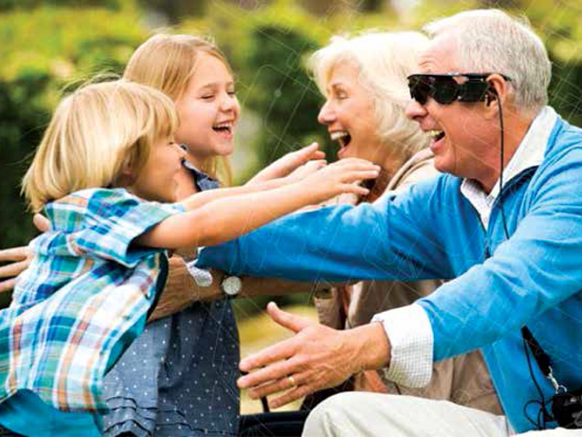 wnuczki biegną do dziadków się przytulić, mężczyzna ma specjalne okulary dla osób niewidomych i niedowidzących 