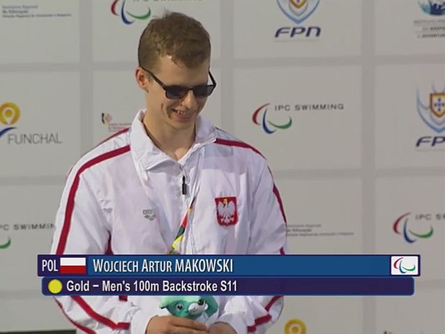 Uśmiechnięty Wojciech Makowski ze złotym medalem na szyi podczas ceremonii medalowej