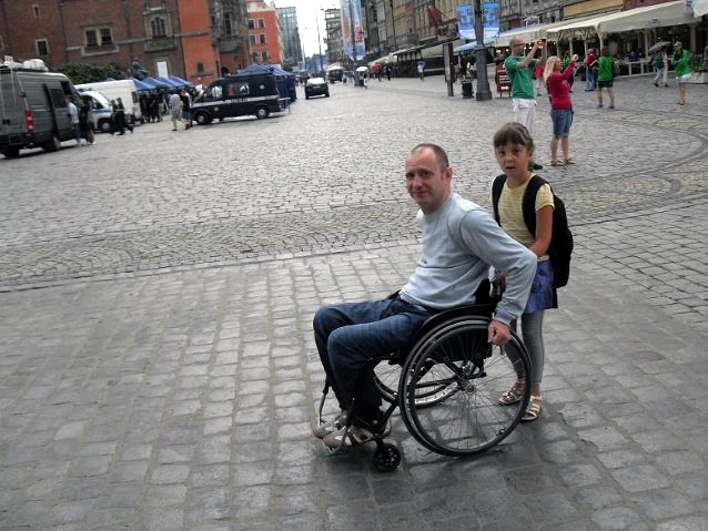 dziewczynka popycha tatę na wózku po szpilkostradzie