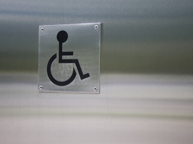 metalowy znak niepełnosprawności przyczepiony na metalowej ścianie