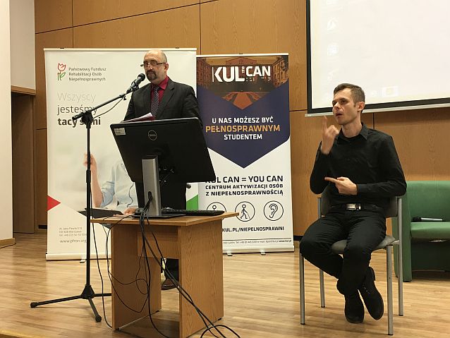 Dyrektor Mirosław Przewoźnik za mównicą, obok siedzi tłumacz języka migowego