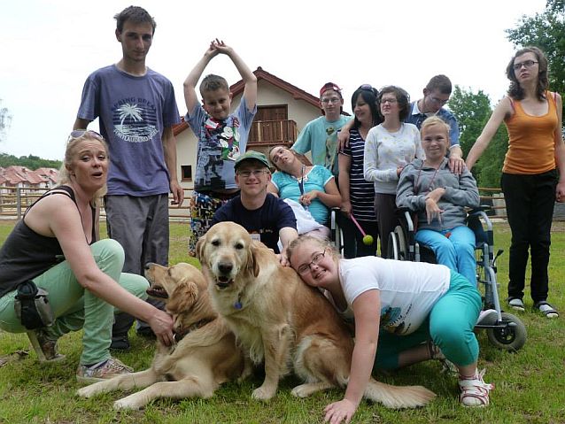 Grupa dzieci i terapeuci na wspólnym zdjęciu z dwoma psami