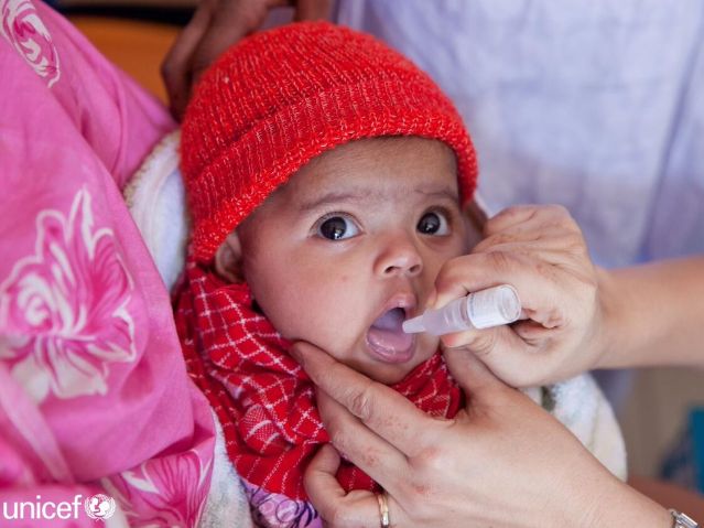 Mała dziewczynka przyjmuje na język kroplę szczepionki