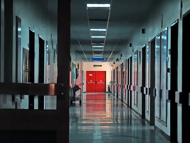 Szpitalny korytarz, na końcu czerwone podwójne drzwi