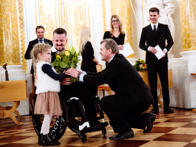 Krzysztof Stern podczas odbierania statuetki wyróżnienia Człowiek bez barier, obok mała córka, której mężczyzna wręcza kwiaty