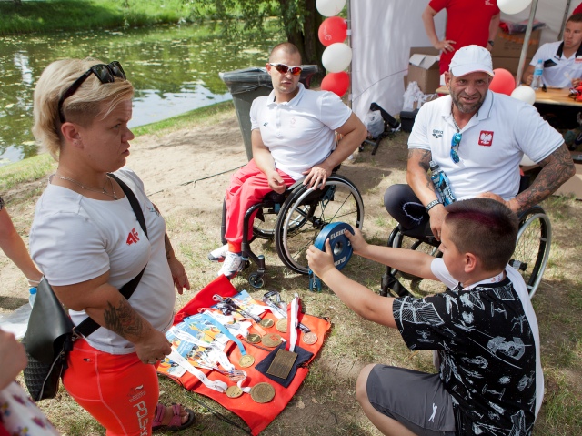 Chłopczyk ogląda medale paraolimpijskie zdobyte przez sportowców w podnoszeniu ciężarów