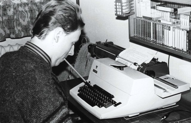 Piotr Pawłowski pisze na maszynie za pomocą trzymania w ustach ołówka lub długopisa
