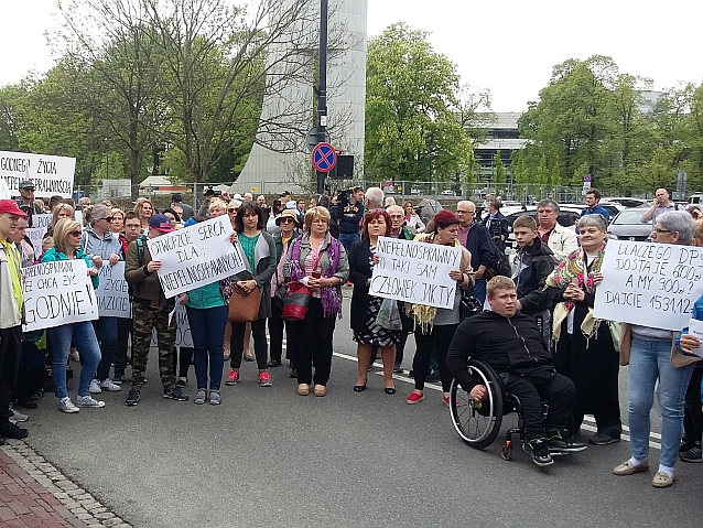 Manifestujący stoją na ulicy z transparentami