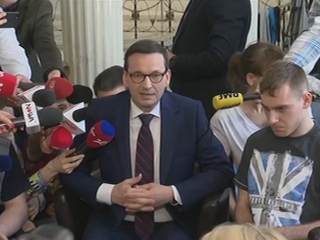 Premier Mateusz Morawiecki siedzi w otoczeniu młodych osób na wózkach i ich rodziców