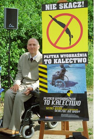 Piotr Pawłowski obok plakatu Płytka wyobraźnia to kalectwo