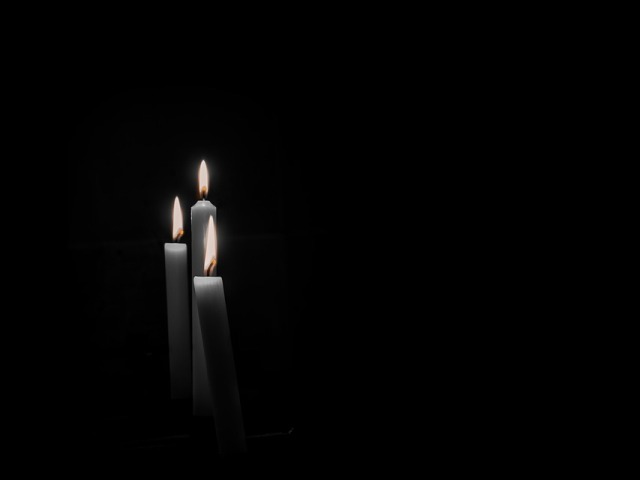 trzy białe świeczki na czarnym tle