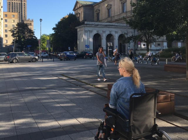 młoda kobieta na wózku elektrycznym przemieszcza się niedaleko przy Pałacu Kultury i Nauki w Warszawie
