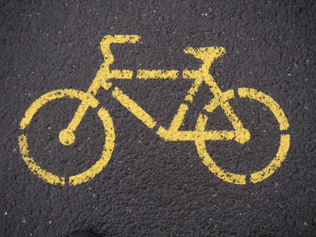żółty znak roweru na ścieżce rowerowej