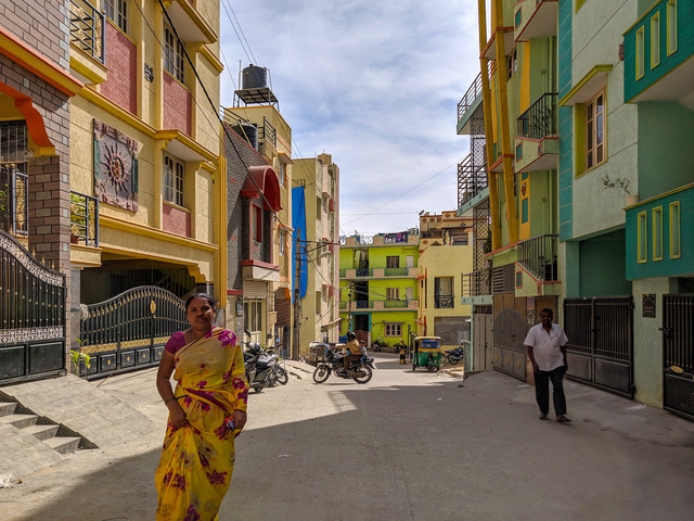 Kolorowe osiedle, na pierwszym planie kobieta w kolorowym ubraniu