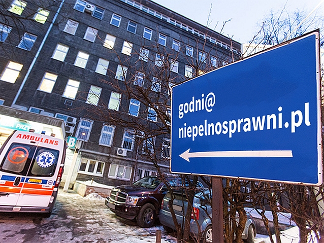 Karetka stoi przed szpitalem. Obok tablica z adresem e-mail: godni@niepelnosprawni.pl