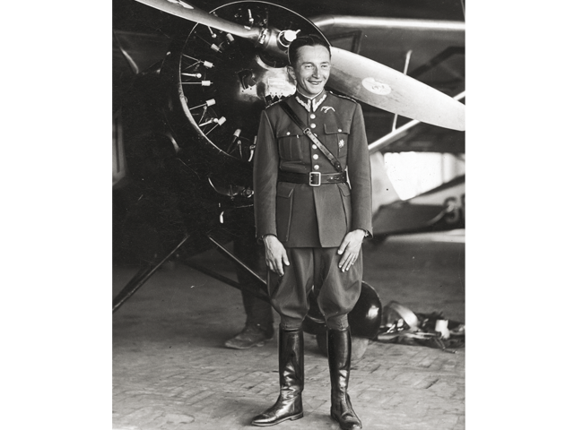 Jerzy Bajan w mundurze lotnika stoi przed śmigłem stojącego za nim samolotu