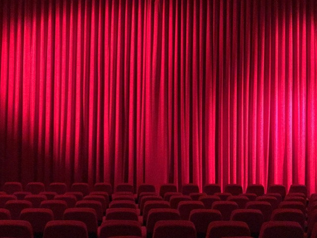 pusta sala kinowa z czerwonymi fotelami i czerwoną kotarą
