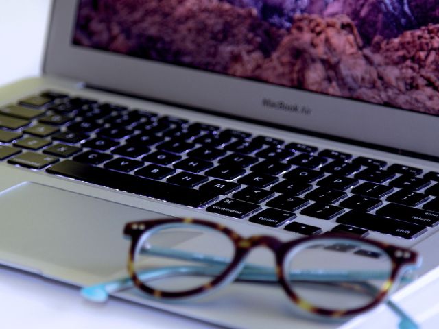 laptop przy którym leżą okulary