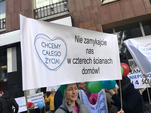 kobieta z transparentem Chcemy całego życia. nie zamyajcie nas w czterech ścianach