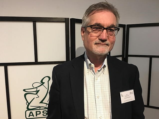 Profesor Michael Wehmeyer pozuje do zdjęcia, w tle napis: APS