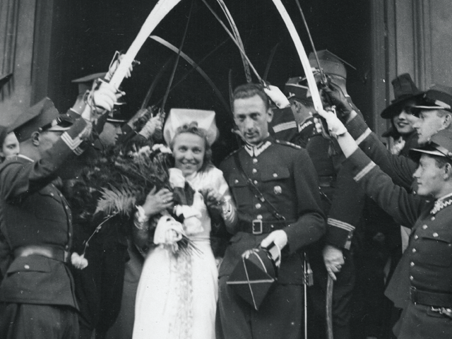 Roman Rożałowski wychodzi z kościoła z nowo poślubioną żoną. Nad nimi żołnierze trzymają szable