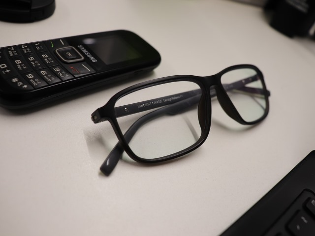 telefon komórkowy leży na stole obok okulary w czarnych oprawkach