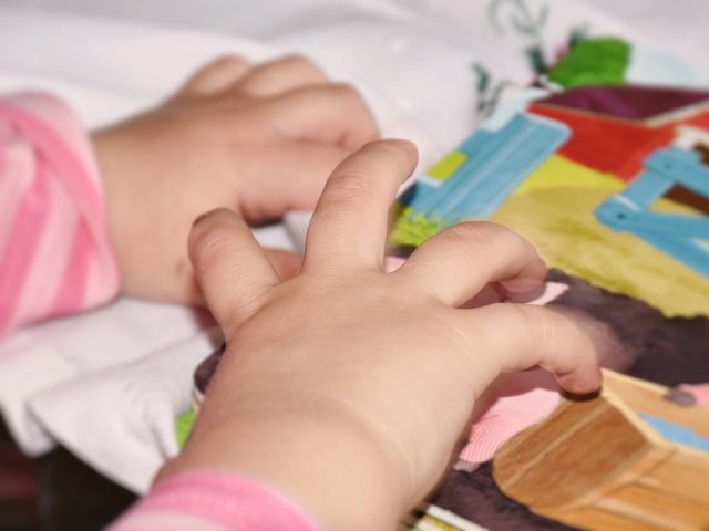 dziecięce ręce dotykają obrazkowej książeczki