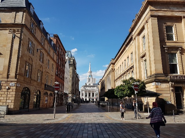 pusta ulica w Glasgow budynki po obu stronach na końcu ulicy biały budynek z wieżą na ulicy tylko trzy osoby