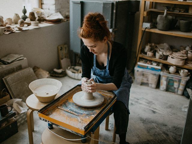 młoda kobieta w pracowni ceramicznej wyrabia coś z gliny