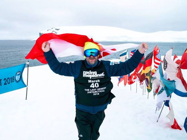 Marek Rybiec na Antarktydzie trzyma flagę Polski