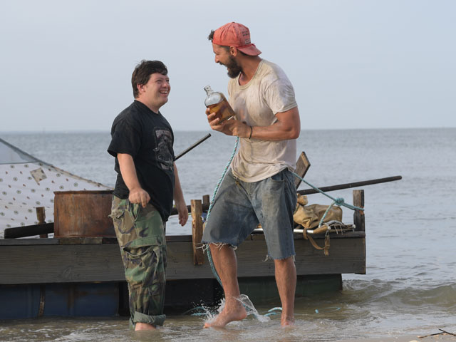 Dwóch bohaterów filmu Zac i Tyler śmieją się stojąc po kostki na brzegu morza