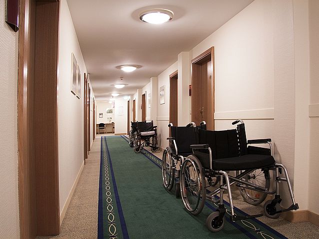 Puste wózki inwalidzkie stoją na korytarzu prowadzącym do wielu pokoi