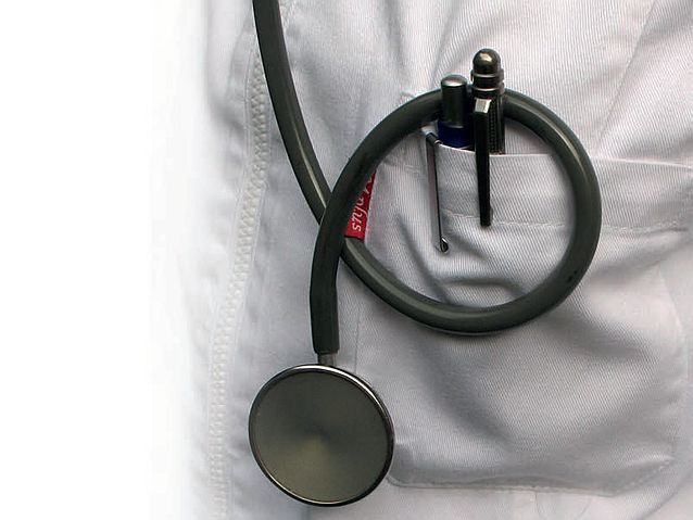 Końcówka stetoskopu wisząca na lekarskim fartuchu